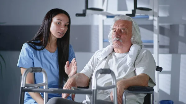 Fisioterapista donna che parla con il paziente anziano di camminare frame — Foto Stock