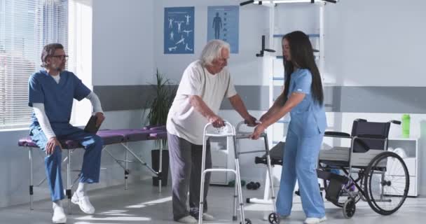 Реабілітаційні терапевти навчають літнього чоловіка ходити — стокове відео