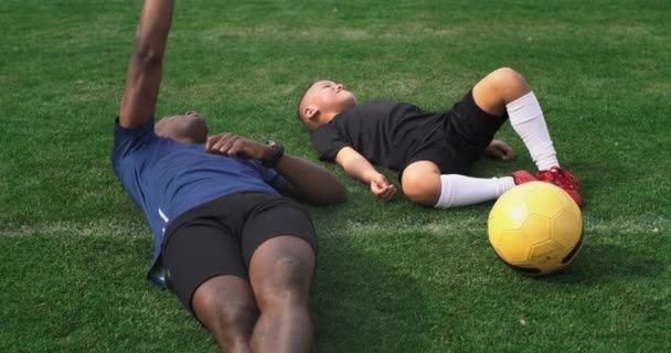 Père et fils divers regardant le ciel après l'entraînement de football — Video