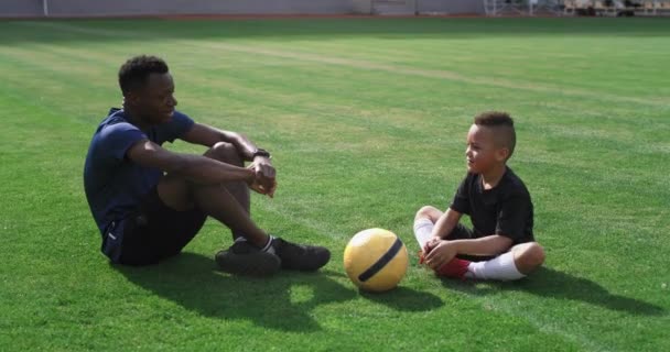 Diverso entrenador y niño hablando en el campo de fútbol — Vídeos de Stock