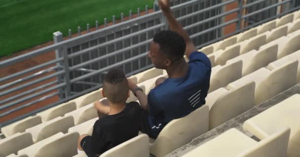 Různorodý muž a chlapec podpůrný tým na stadionu — Stock video