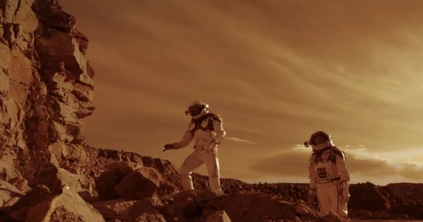 Astronauten beklimmen rotsen en kijken weg op Mars — Stockvideo