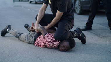 Polis ağlayan siyah adama kelepçe takıyor.