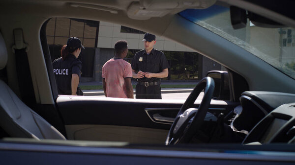 Diverse police officers checking documents of black driver