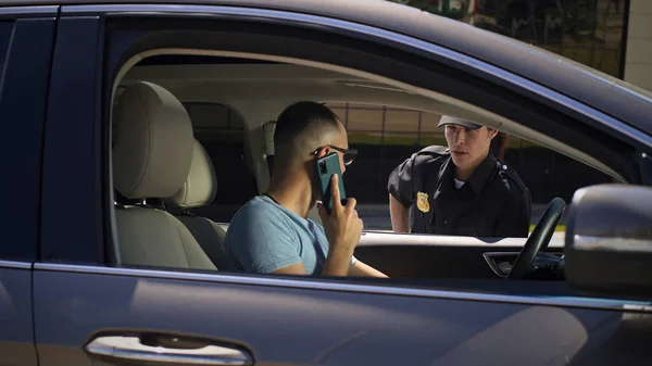 Роздратований водій зі смартфоном, що розмовляє з поліцейським — стокове фото