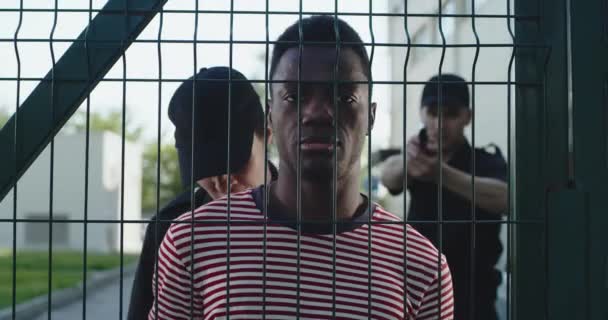 Politieagenten arresteren zwarte man in de buurt van raster — Stockvideo
