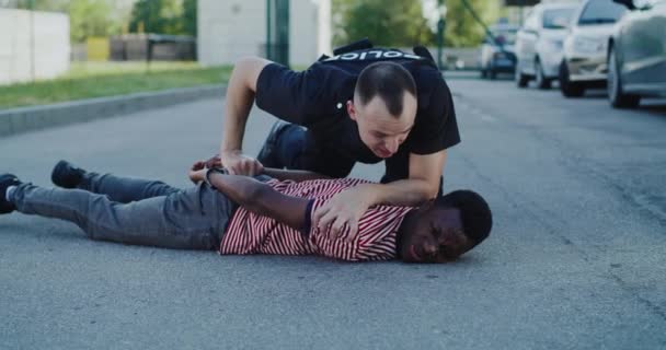 Polis förhör svart man på marken — Stockvideo