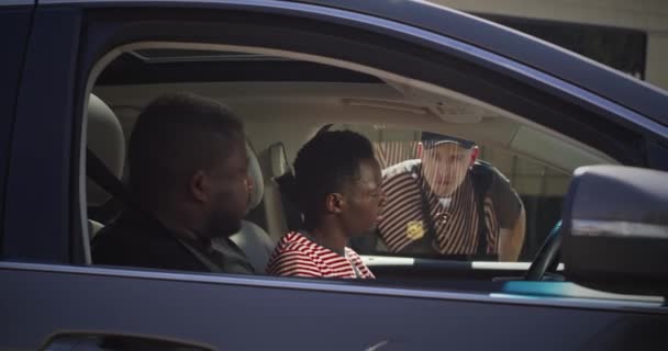 Poważny policjant sprawdzający czarnych mężczyzn w samochodzie — Wideo stockowe