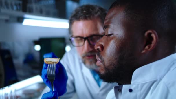 Hombre afroamericano comiendo nugget de carne de célula cerca de colega — Vídeo de stock