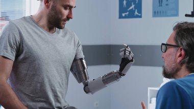 Mutlu hasta, doktorun yanında biyonik kol kullanmayı öğreniyor.