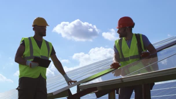 Ingenieros masculinos examinando paneles fotovoltaicos en día soleado — Vídeos de Stock