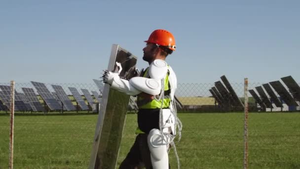 Mužský technik v exoskeletonu nesoucí fotovoltaický panel — Stock video
