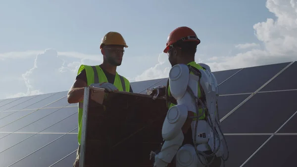 Uomo in esoscheletro prendere pannello solare da collega — Foto Stock