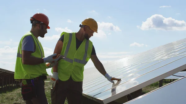 Ingenieros masculinos inspeccionando el panel fotovoltaico juntos —  Fotos de Stock