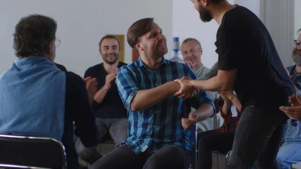 Adsız Alkolikler toplantısında iyileşmiş bağımlıları alkışlayan insanlar