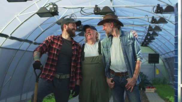 Оптимистичные садовники обнимаются в оранжерее — стоковое видео