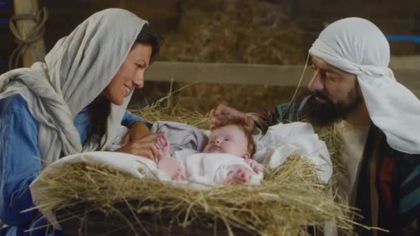 Мария и Иосиф разговаривают с младенцем Иисусом в яслях — стоковое видео