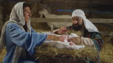 Mary ve Joseph handa bebek İsa 'ya bakıyorlar.