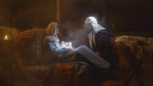 Joseph talking with Mary and baby Jesus in barn — ストック動画