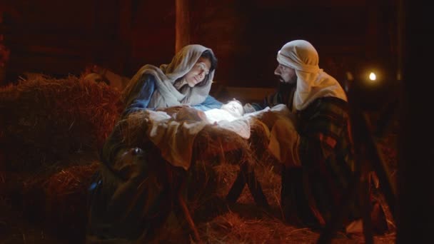 María y José acariciando al niño Jesús en un pesebre iluminado — Vídeo de stock