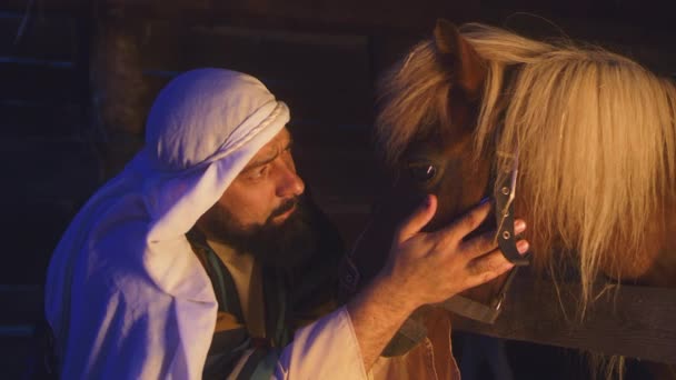 Joseph acariciando caballo en granero oscuro — Vídeos de Stock