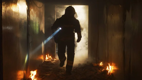 Пожарные бегут по коридору горящего здания — стоковое фото
