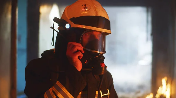 Fireman speaking on radio in burning building — Stock Photo, Image