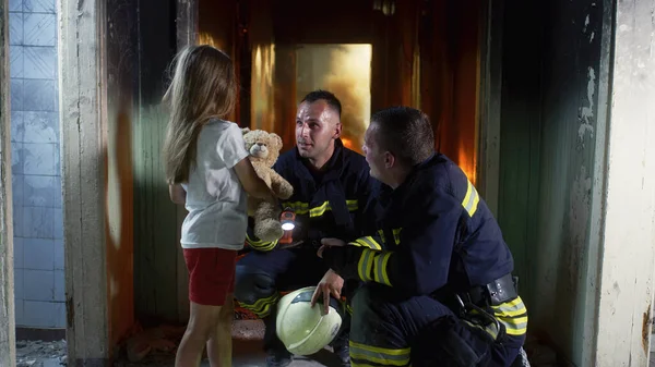 Bombeiros falando e dando brinquedo para menina — Fotografia de Stock