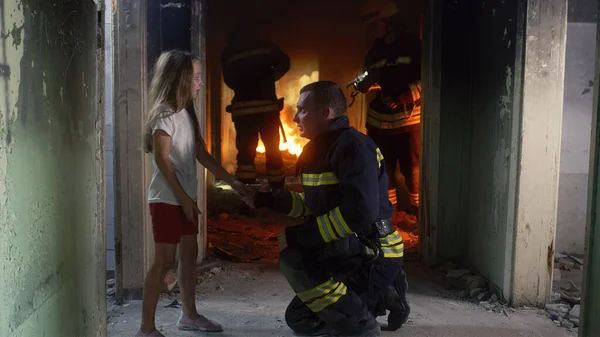 Menina falando com bombeiro em prédio em chamas — Fotografia de Stock
