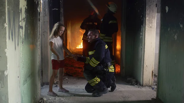 Girl speaking with fireman in burning building — Stock Photo, Image