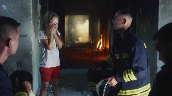 Firemen interrogating saved girl in burning building — Stock Photo, Image