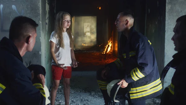 Brandweermannen ondervragen gered meisje in brandend gebouw — Stockfoto