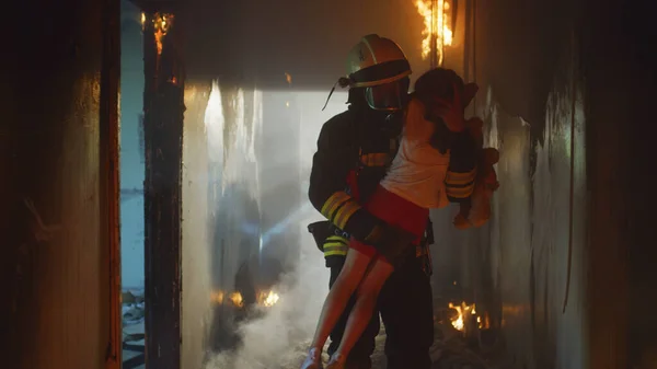 Brandweerman draagt kind heldhaftig door rook en vuur — Stockfoto