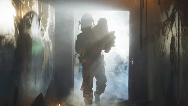 Fireman carrying kid heroically through smoke and fire — Stock Photo, Image