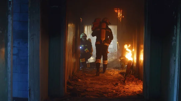 Bomberos corriendo a través del fuego y buscando sobrevivientes — Foto de Stock
