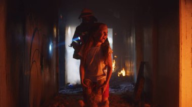 İtfaiyeci çocuğu duman ve yangında kahramanca taşıyor.