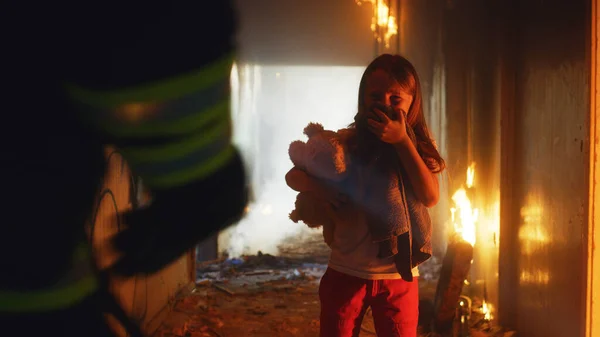 Brandweerman draagt kind heldhaftig door rook en vuur — Stockfoto