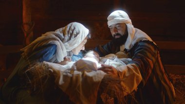Meryem ve Yusuf, aydınlatılmış yemlikte bebek İsa 'yı okşuyor.
