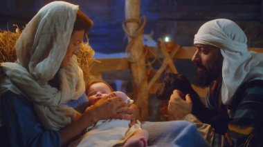 Yusuf kuzuyla, Meryem de bebek İsa ile ahırda.