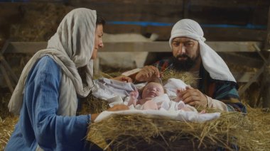 Mary ve Joseph handa bebek İsa 'ya bakıyorlar.