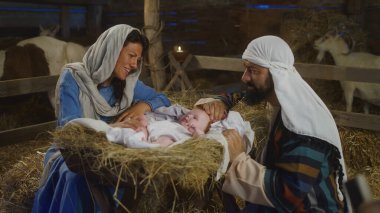 Mary ve Joseph handa bebek İsa 'ya bakıyorlar.