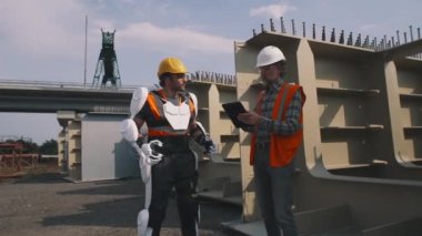 Foreman dış iskeletteki inşaatçıyla konuşuyor.