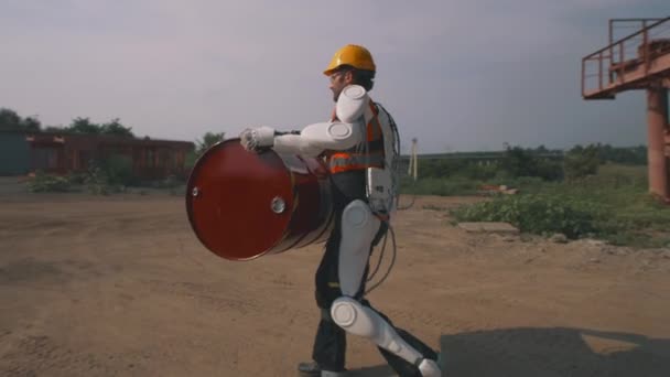 Manlig arbetare i exoskelett transporterar fat — Stockvideo