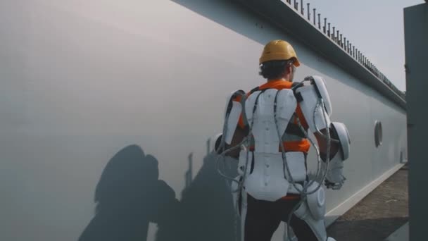 Male builder in exoskeleton walking on construction site — Stock Video