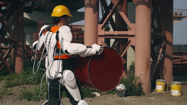 Männlicher Arbeiter im Exoskelett liefert Fass an Vorarbeiter — Stockfoto