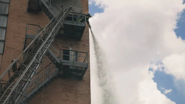 Brandweerman blusser vuur van hoogte — Stockfoto