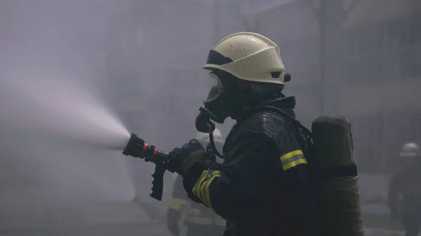 Brandweerman training met waterslang — Stockfoto