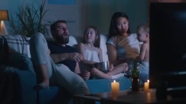 Farklı aileler karanlık oturma odasında film izliyor.
