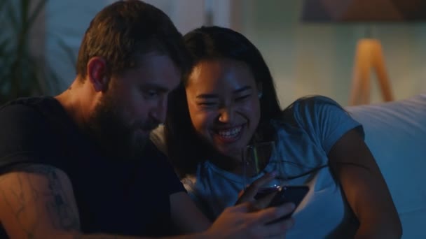 Vielseitiges Paar nutzt Smartphone auf dem Sofa — Stockvideo