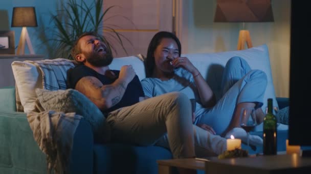Diversa pareja viendo película de comedia en la noche — Vídeo de stock